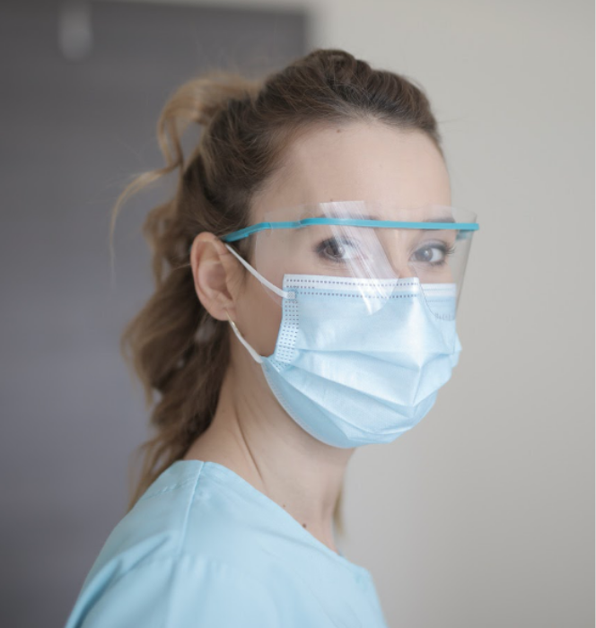 An Infection Preventionist with smiling eyes wearing scrubs, a face mask and an eye mask.